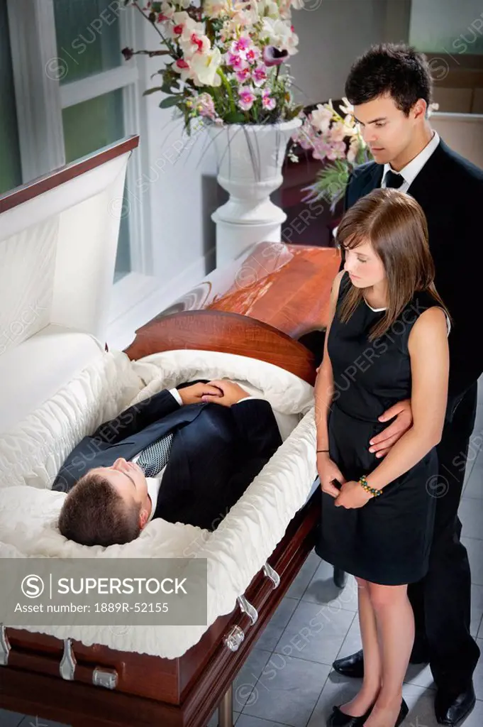 a man and a woman viewing a body in a coffin