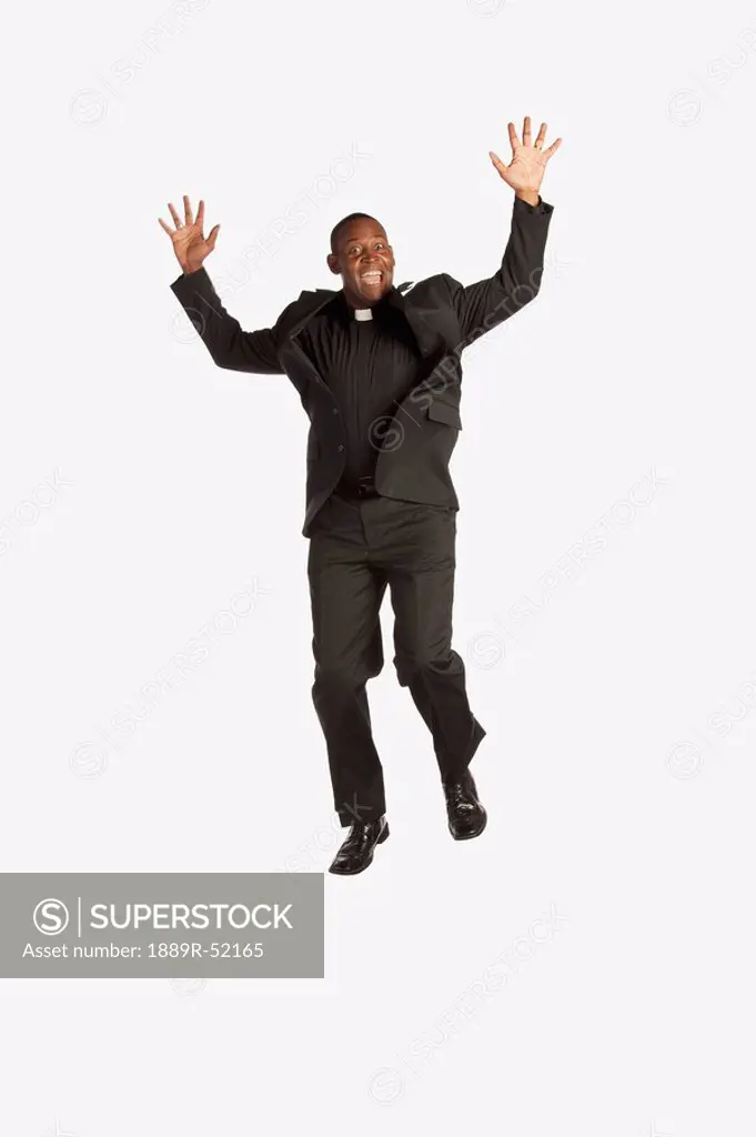 a man wearing a clerical collar and jumping in the air