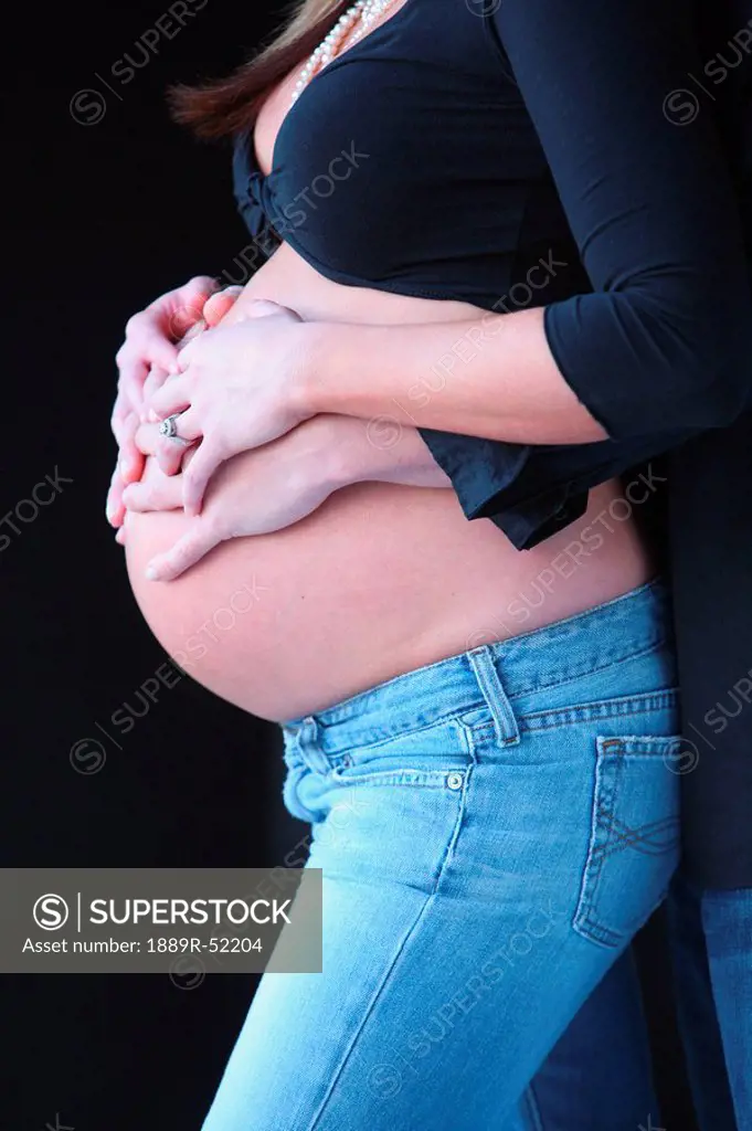 a pregnant woman´s belly held by the woman´s and men´s hands