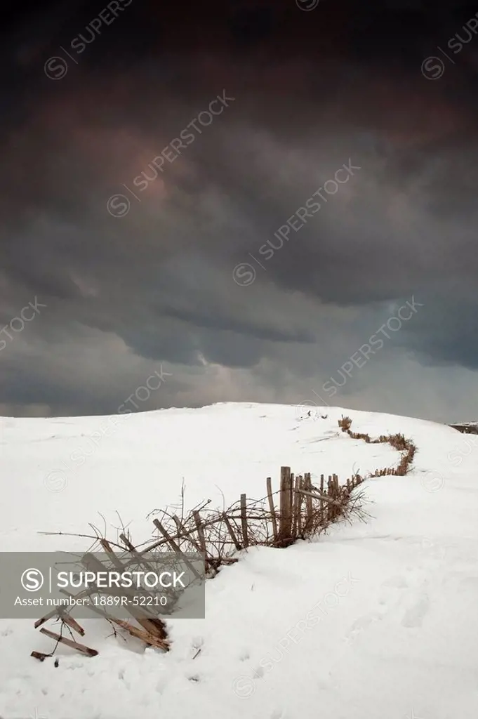 south shields, tyne and wear, england, a fence in a snowy field with a dark sky