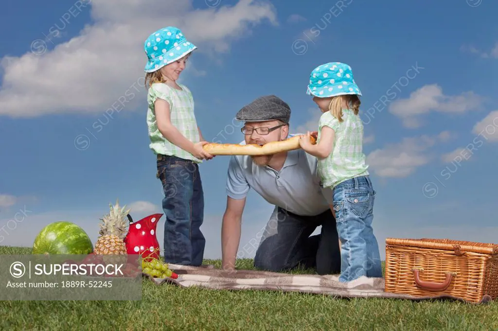 a father and two daughters having a picnic