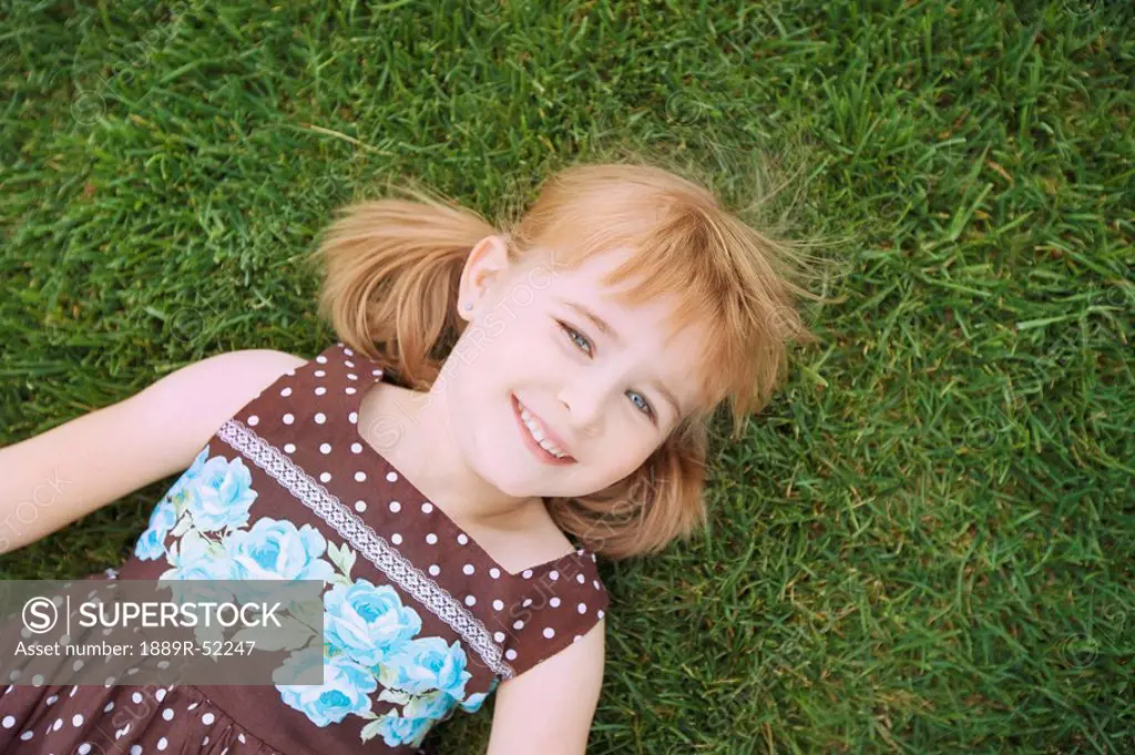 a young girl laying on the grass