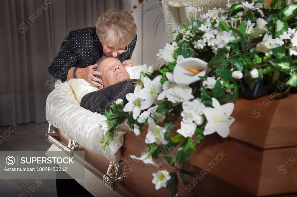 woman kisses her deceased spouse in a coffin
