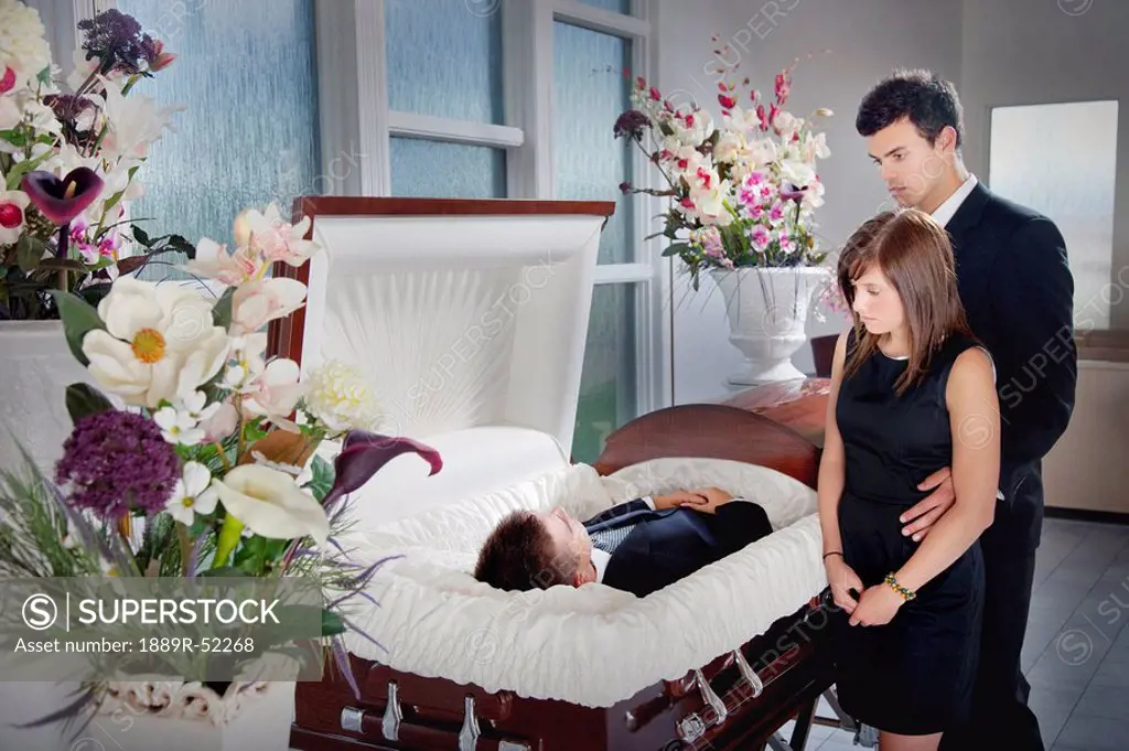 a young couple views a deceased loved one in a coffin
