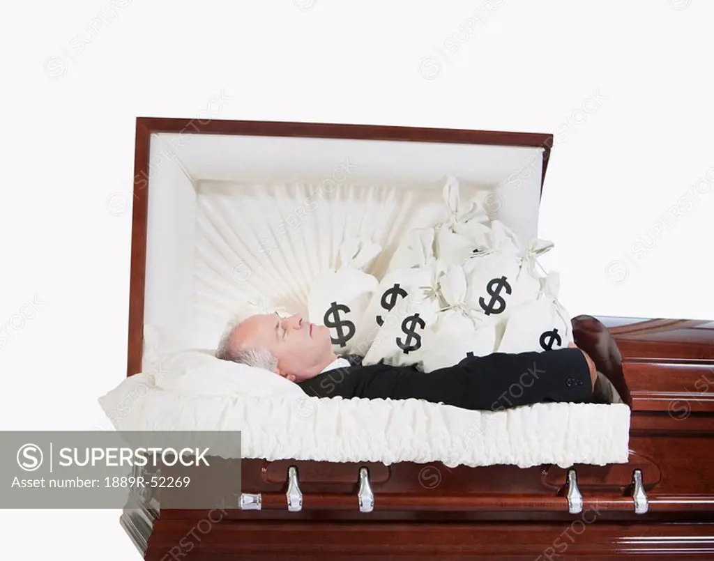 a deceased man in a coffin surrounded by bags of money