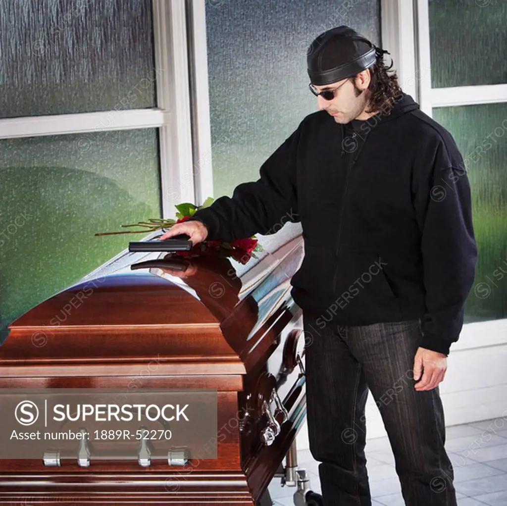 a man laying his gun on top of a coffin