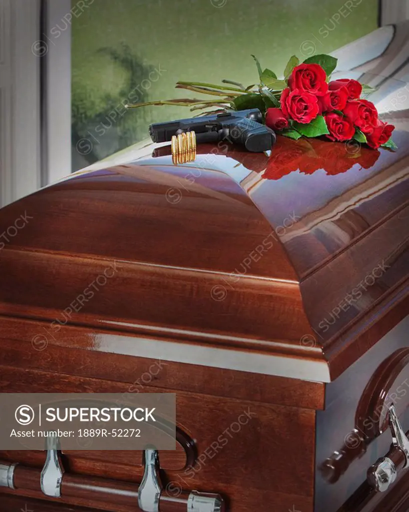 a gun, bullets and bouquet of roses on top of a coffin