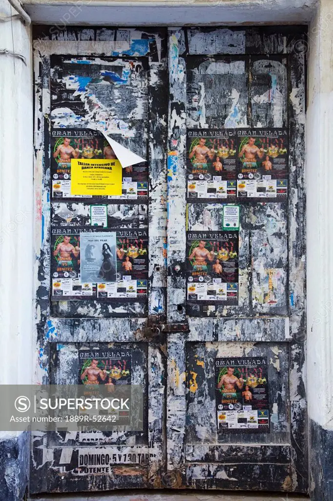 chiclana, andalusia, spain, an old door along the street covered in paper advertisements
