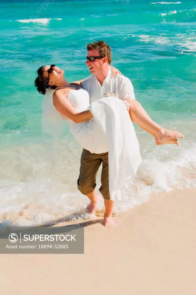 akumal, riviera maya, mexico, a groom carrying the bride on the beach at gran bahia principe tulum all_inclusive resort