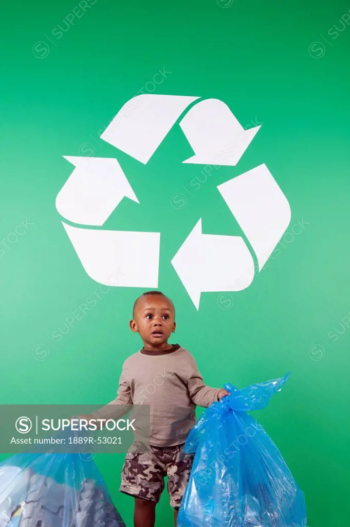 a young boy with bags of recycle items under a recycling sign