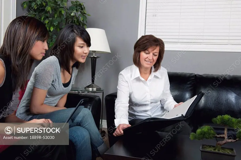 a businesswoman showing a document to two young women