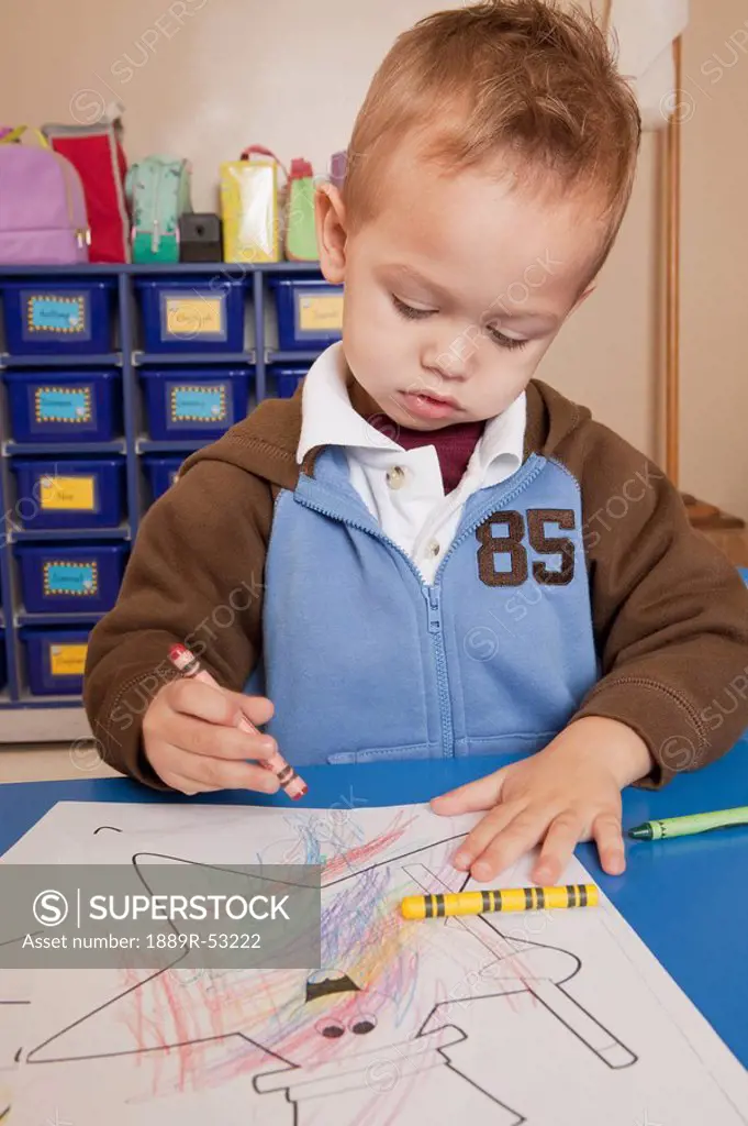fort lauderdale, florida, united states of america, a young boy coloring at a table in a classroom