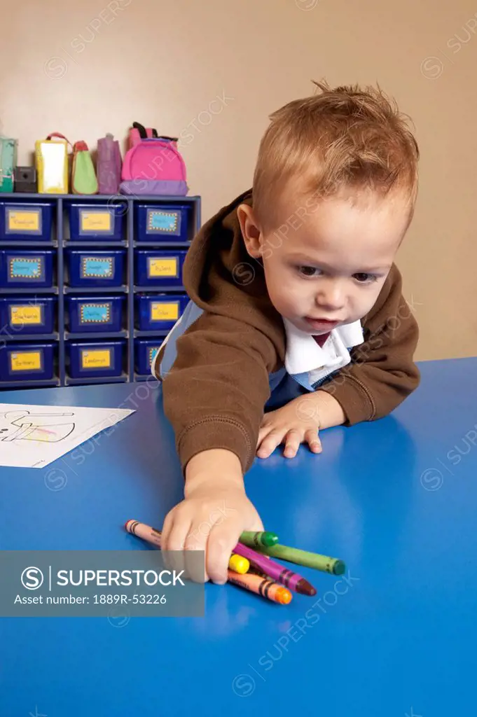 fort lauderdale, florida, united states of america, a young boy reaching for crayons on a table in a classroom
