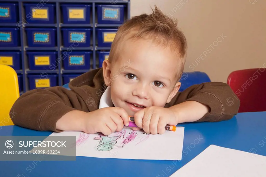 fort lauderdale, florida, united states of america, a young boy coloring at a table in a classroom