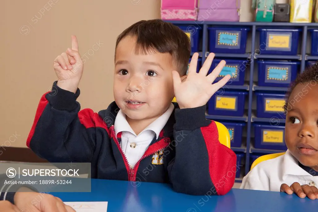 fort lauderdale, florida, united states of america, a young boy holding up six fingers at a table in a classroom