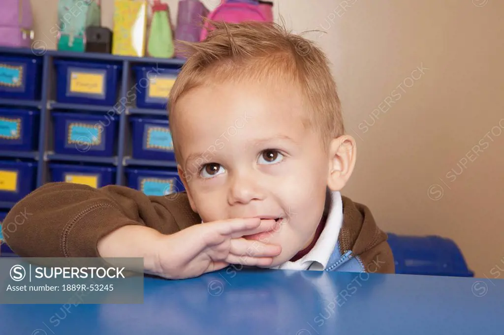 fort lauderdale, florida, united states of america, a young boy sitting at a table in a classroom