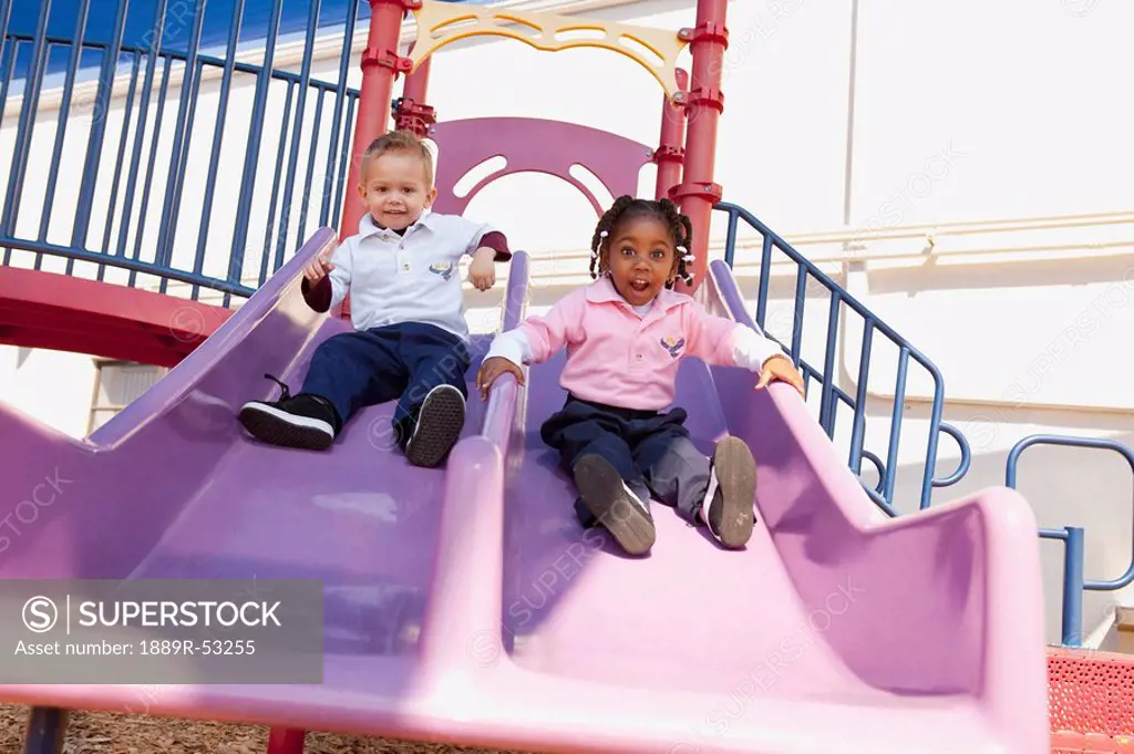 fort lauderdale, florida, united states of america, two young children going down the slide at the playground