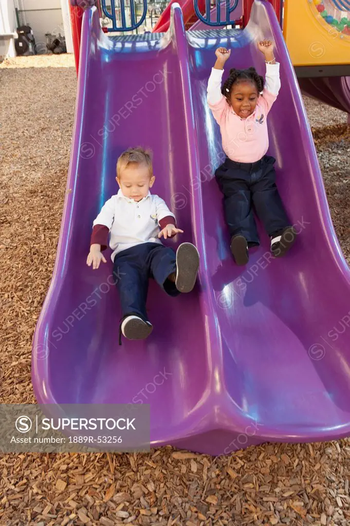 fort lauderdale, florida, united states of america, two young children going down the slide at a playground