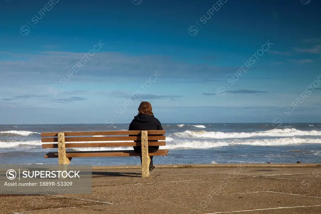 saltburn, teesside, england, a woman sitting on a bench and watching the waves on the water
