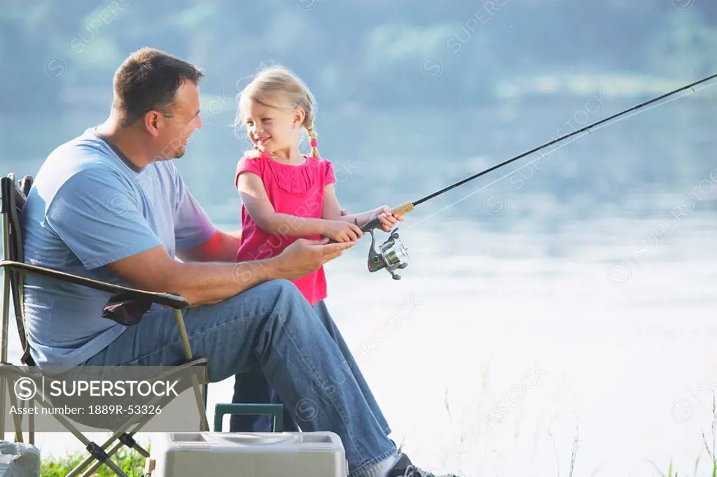 a father fishing with his young daughter