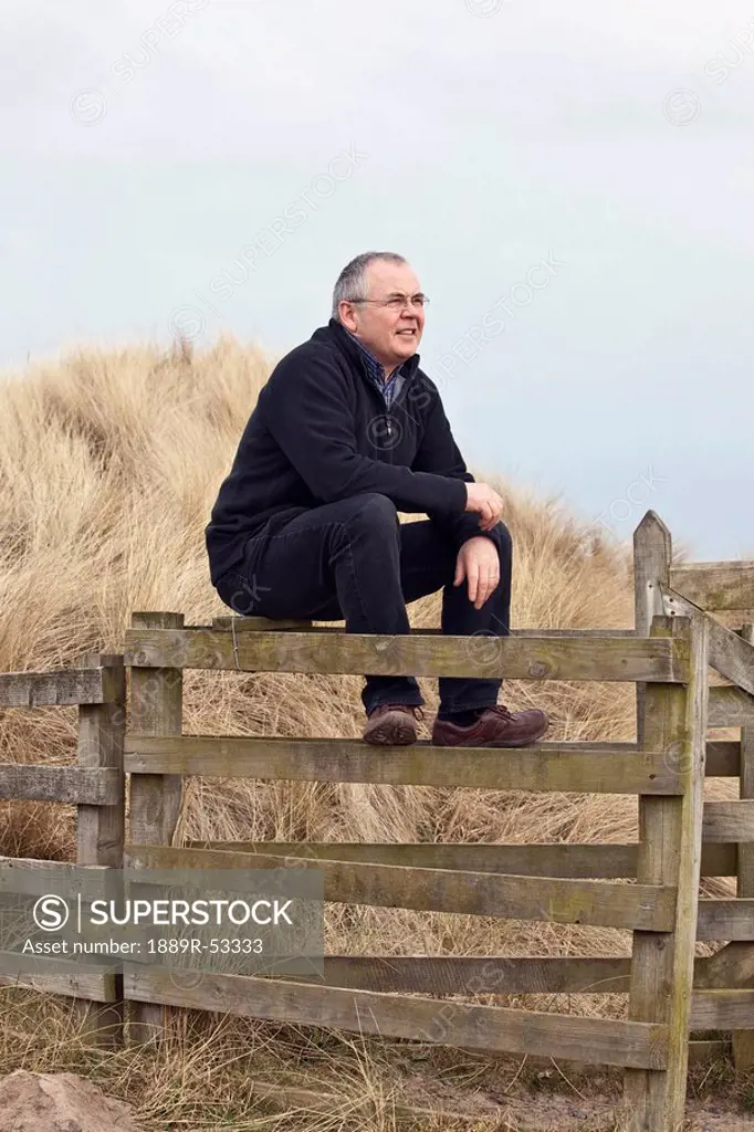 northumberland, england, a man sitting on a fence