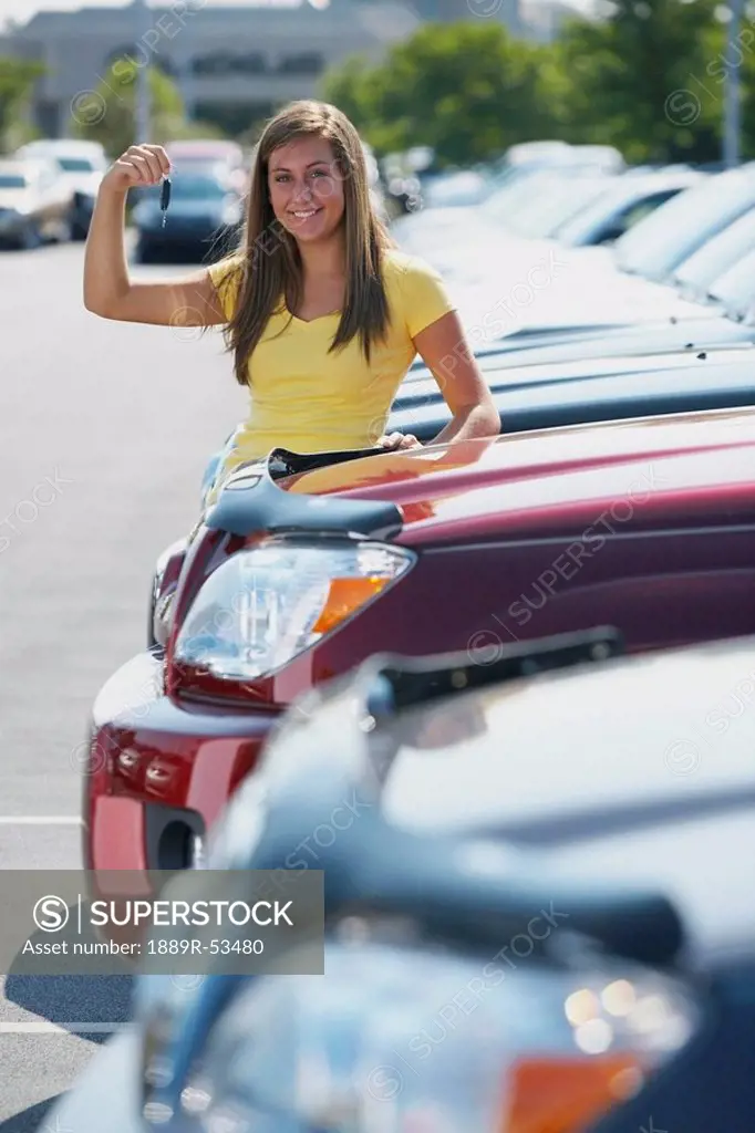 a young woman with keys to a vehicle in a car dealership