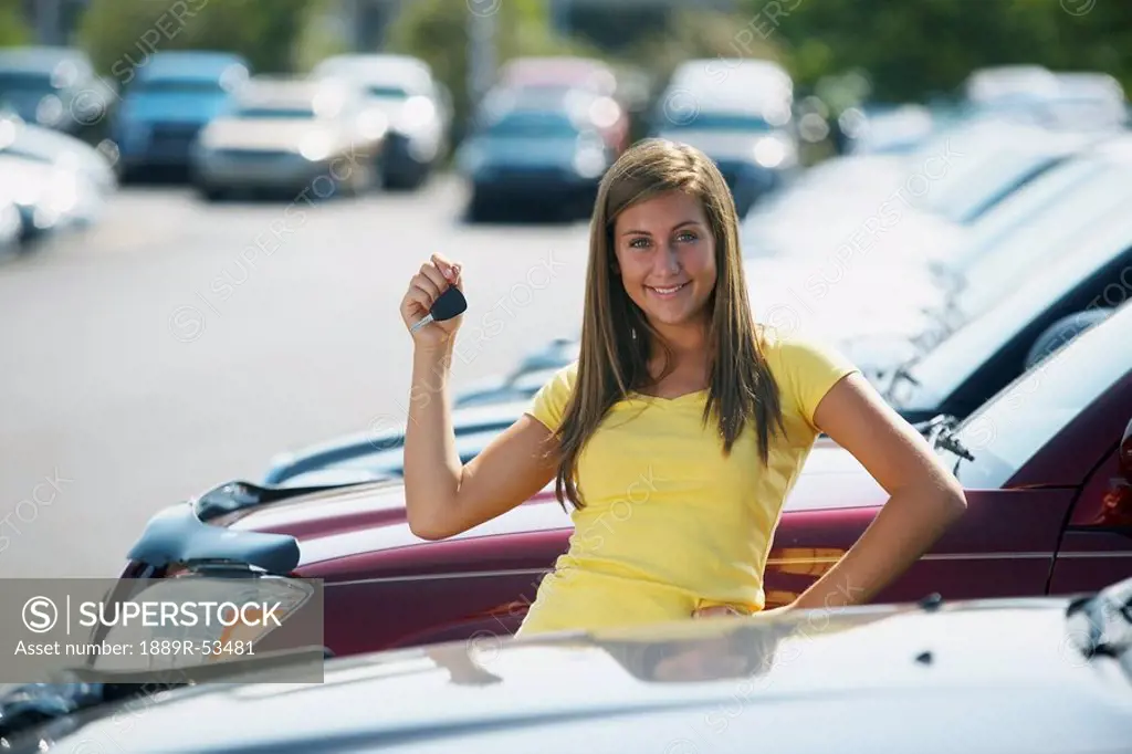 a young woman with keys to a vehicle in a car dealership