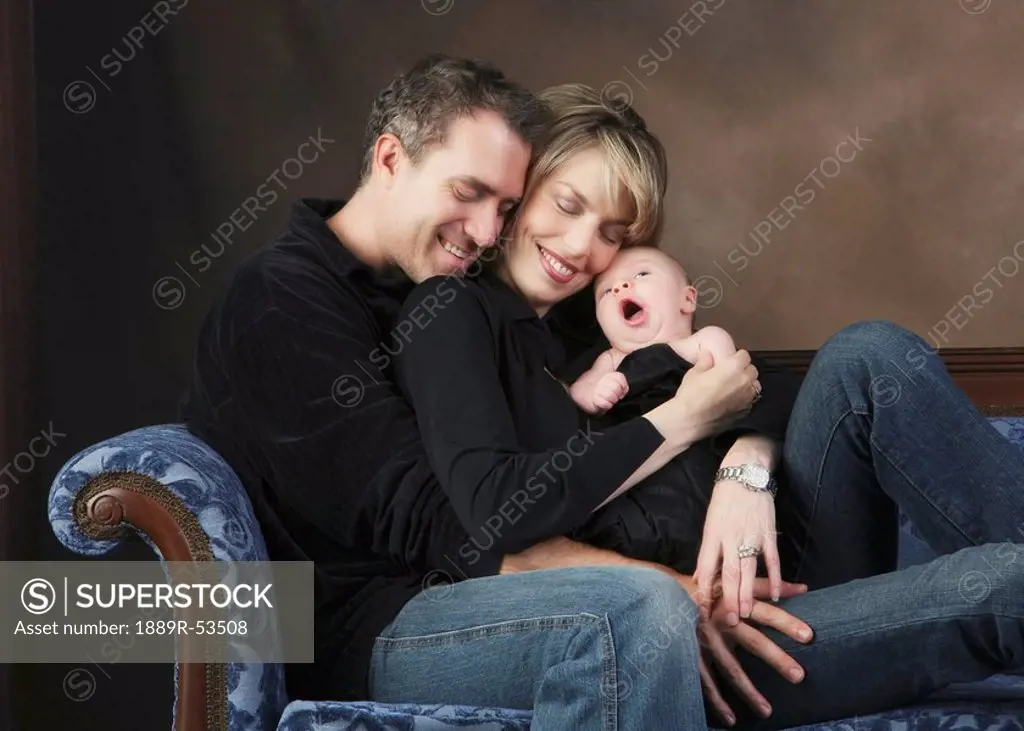 a family sitting on a couch with a baby yawning