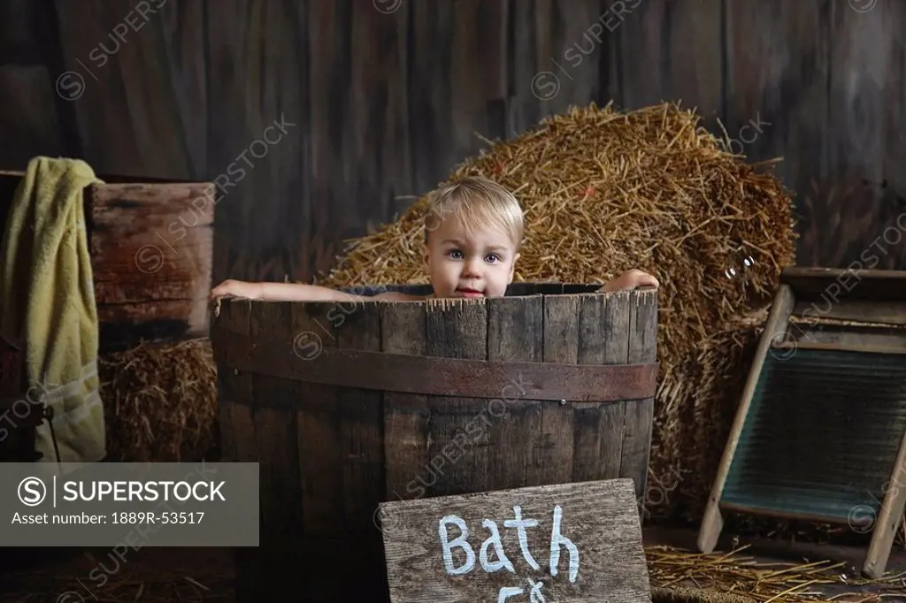 a toddler having a bath in a barrel