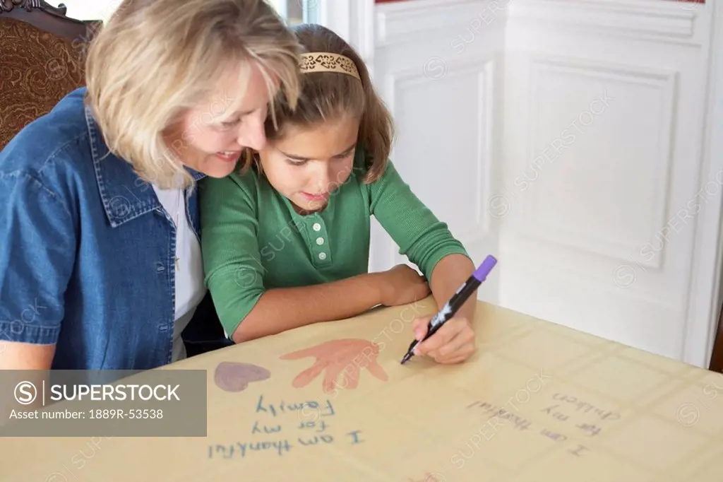 a girl with her mother drawing a picture saying ´i am thankful for my family´