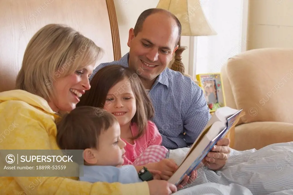 a mother and father reading with their children at bedtime