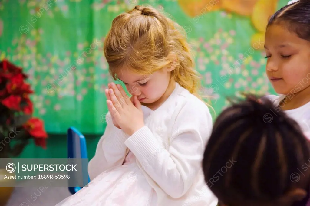 a young girl bowing her head in prayer