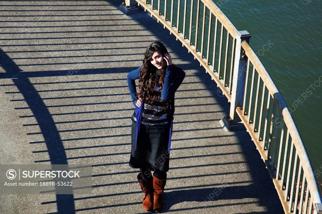 a girl standing beside a railing along the water