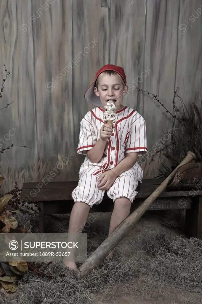 a boy wearing a baseball uniform and eating an ice cream cone