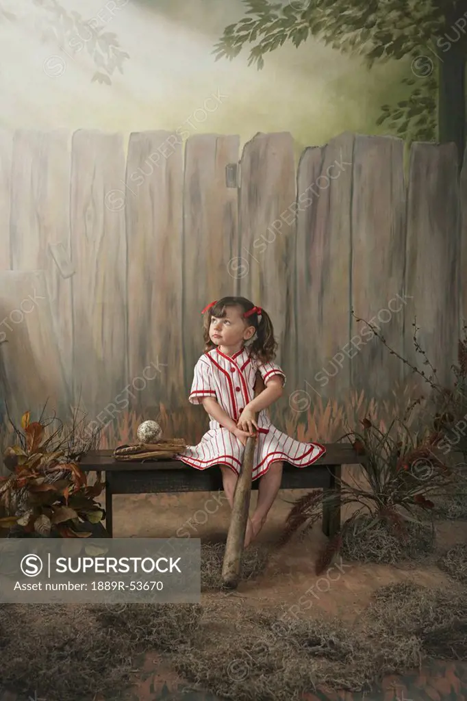 a girl sitting on a bench wearing a vintage girl´s baseball uniform