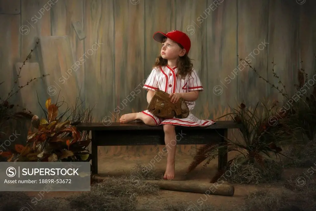 a girl sitting on a bench wearing a vintage girl´s baseball uniform
