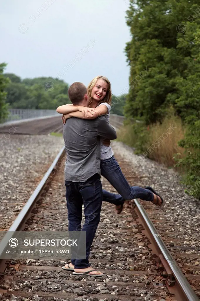 a couple hugging on the train tracks