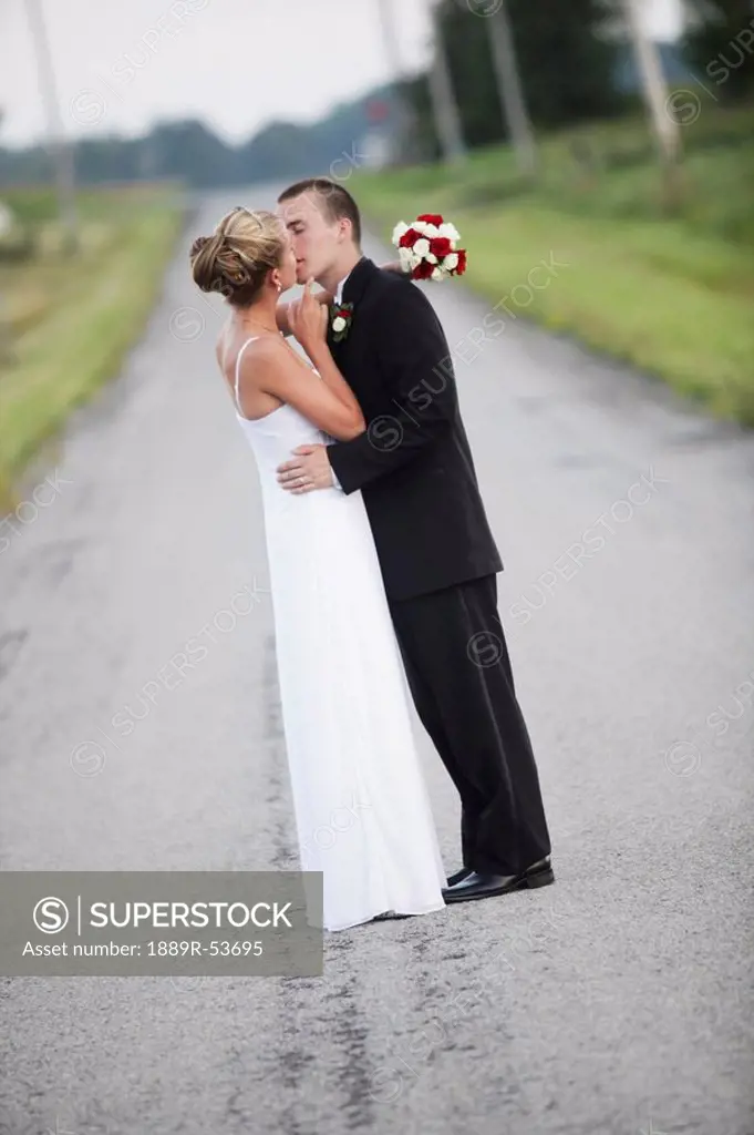 a bride and groom kissing in the middle of the road
