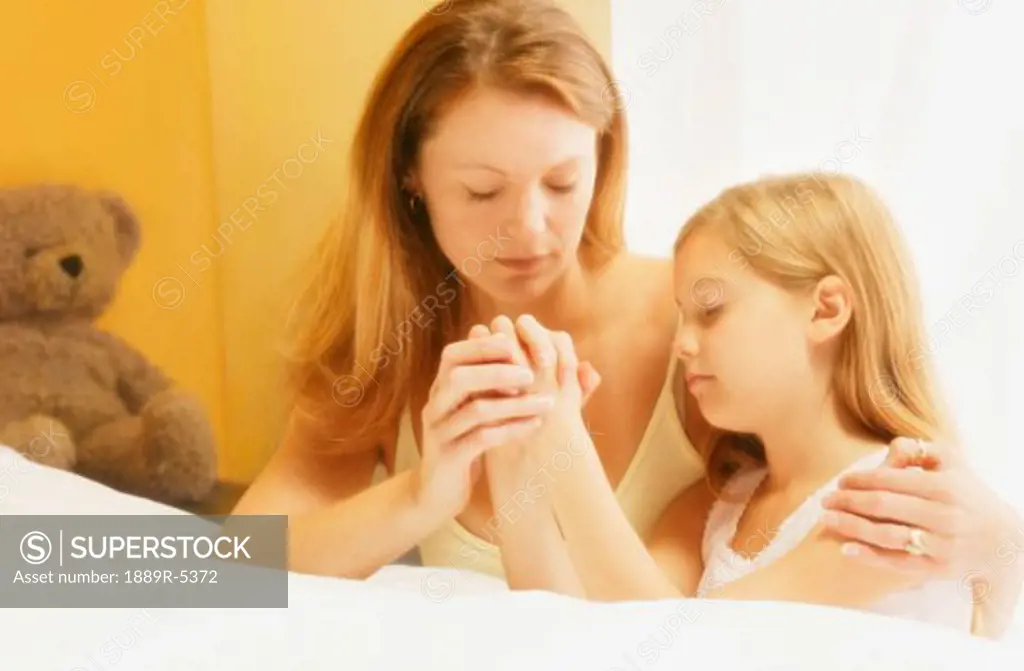 Mother praying with daughter