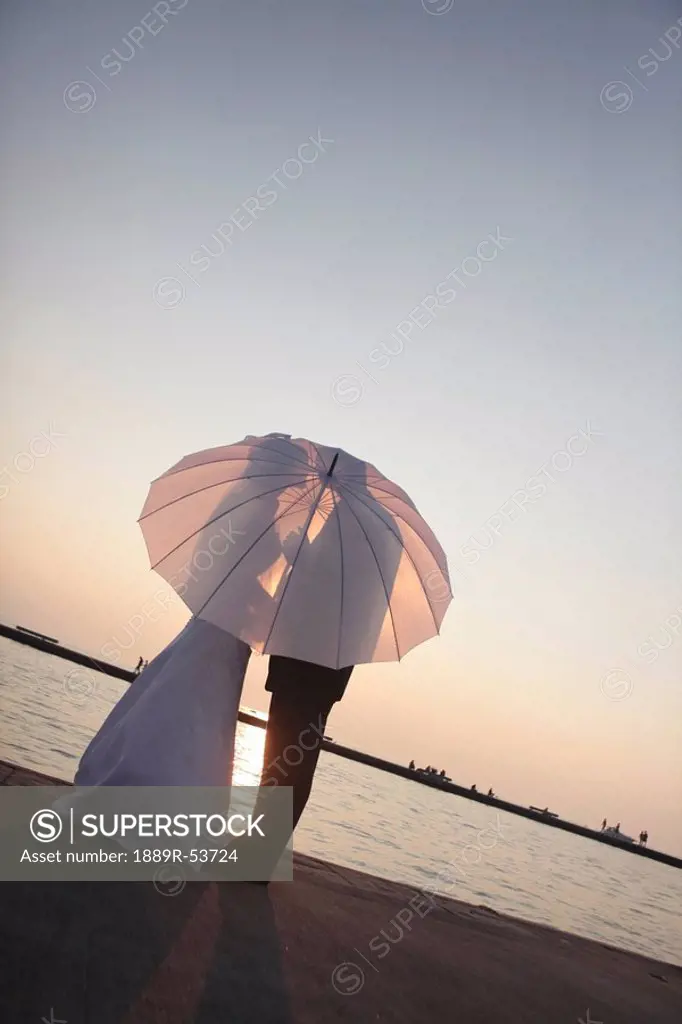 silhouette of a bride and groom behind an umbrella