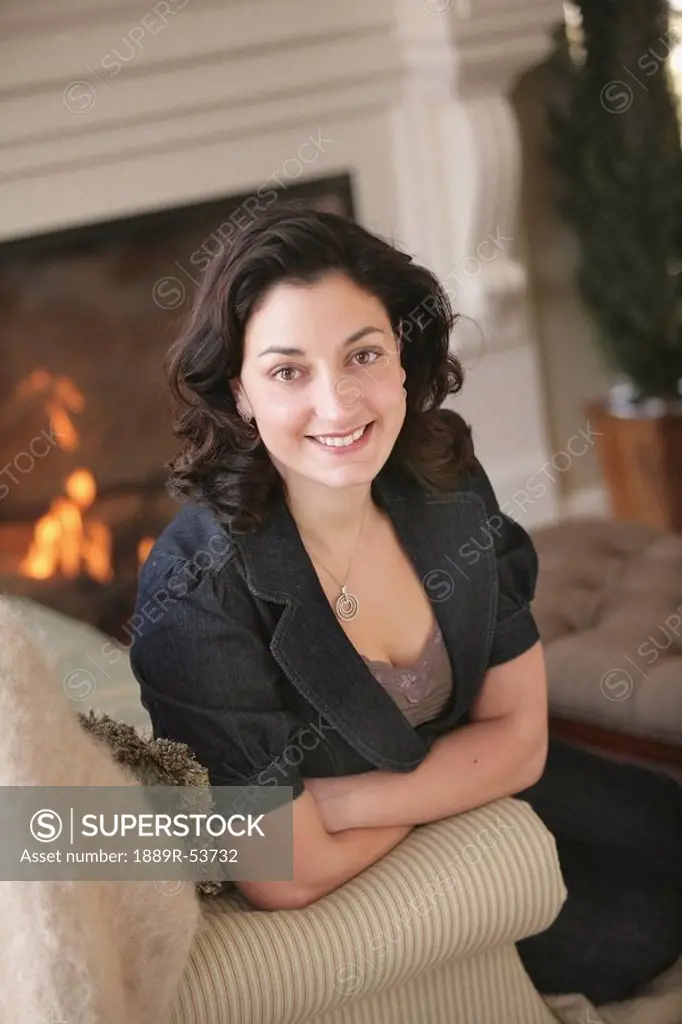 a woman sitting on a couch beside a fireplace