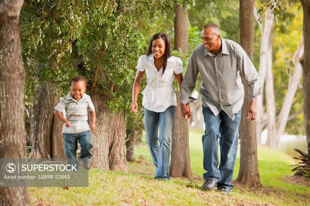 fort lauderdale, florida, united states of america, a father and mother with their young son walking through a park