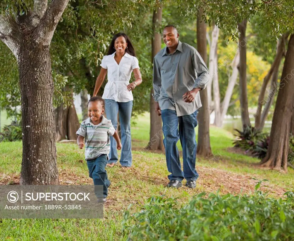 fort lauderdale, florida, united states of america, a mother and father chasing their young son through a park
