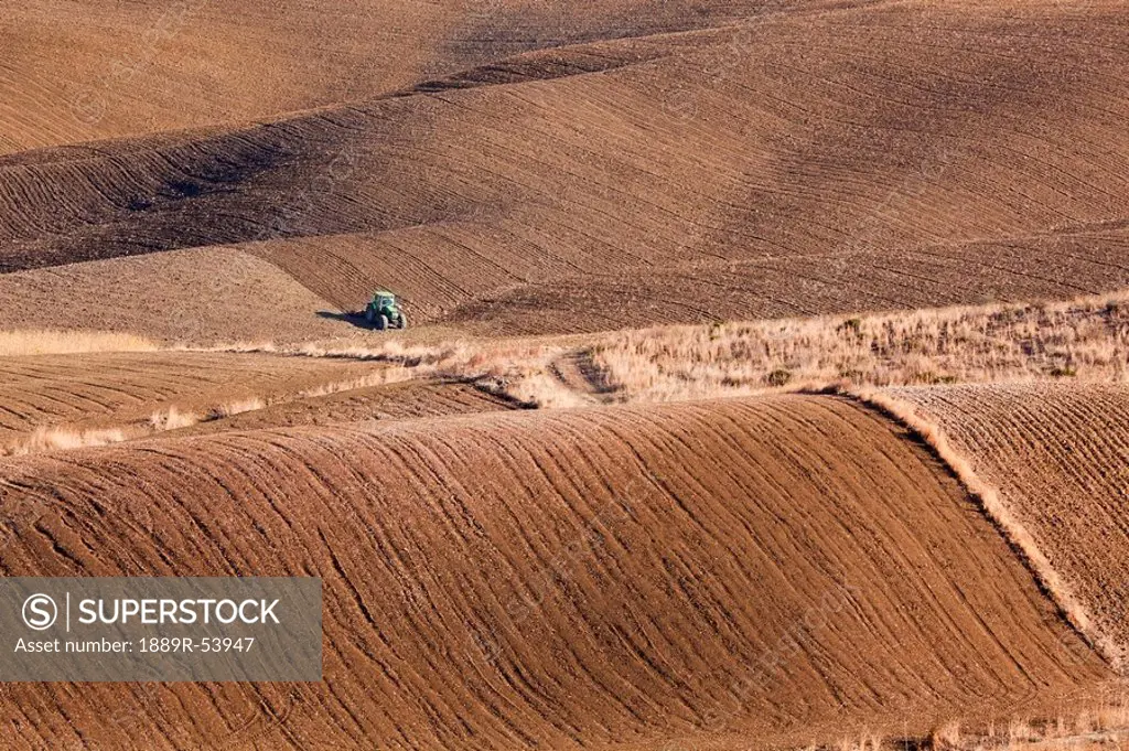 malaga, spain, green tractor ploughing fields near alhaurin el grande