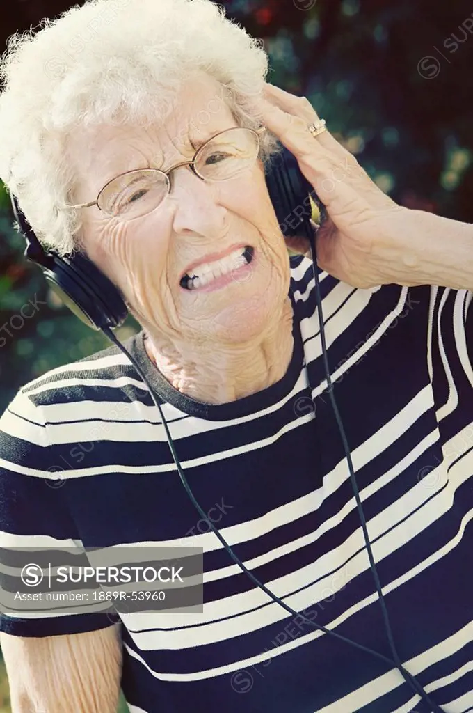 sherwood park, alberta, canada, a senior woman cringing at the music coming through her headphones