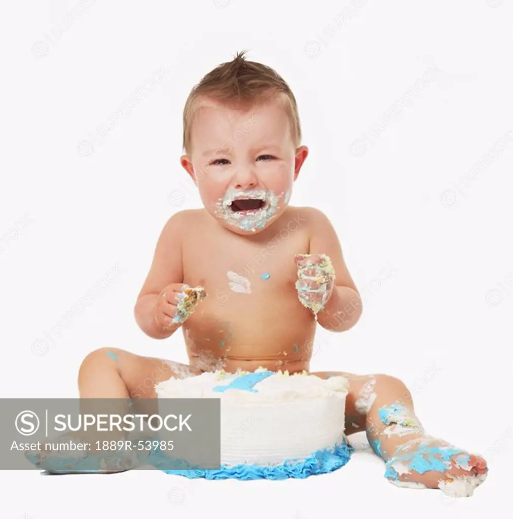edmonton, alberta, canada, a baby crying and covered in icing as he eats his birthday cake with his hands