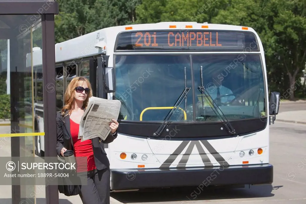 st. albert, alberta, canada, a woman waits at a bus stop as the bus approaches