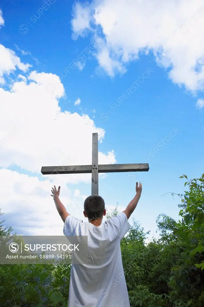 A Teenage Boy With Arms Raised Towards The Cross