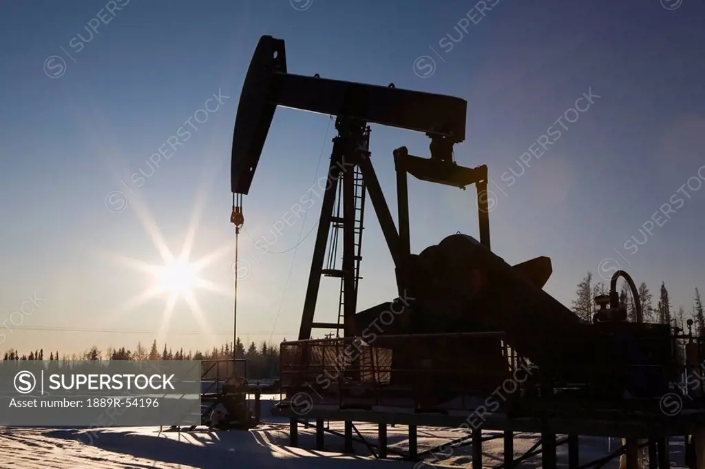 edson, alberta, canada, silhouette of a pump jack with a sunburst in winter