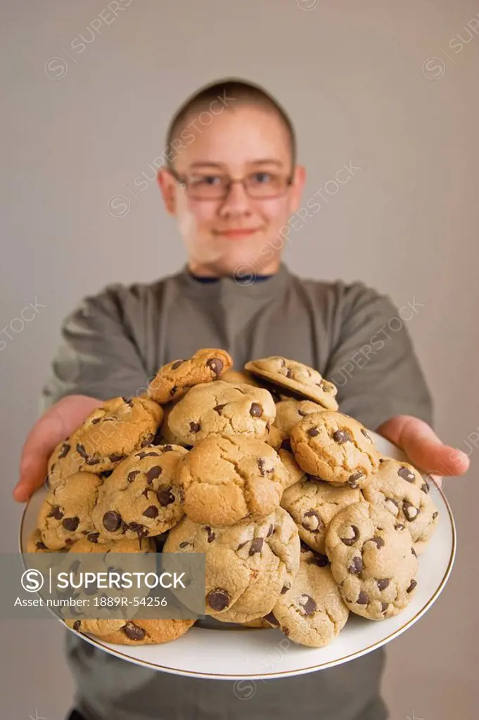 A Boy Holding A Plate Of Chocolate Chip Cookies